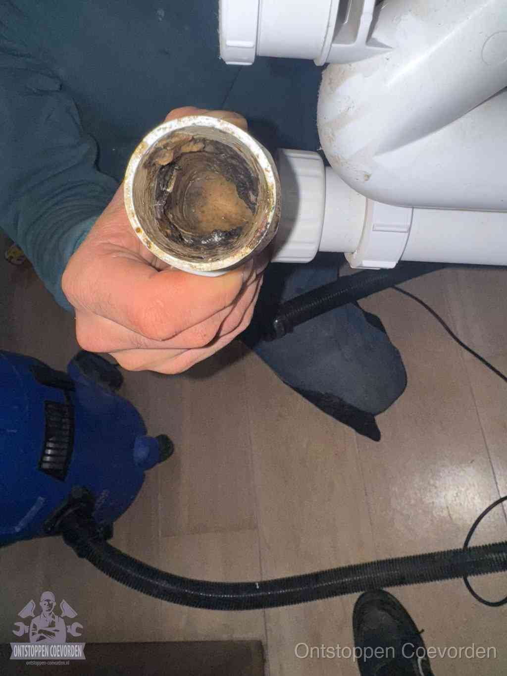 Een losgekoppelde afvoerbuis die van binnen volledig is dichtgeslibd met vet en aanslag, de meest voorkomende oorzaak van een verstopte gootsteen in Coevorden
