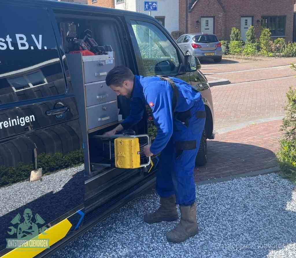 Een monteur pakt buiten op de oprit gereedschap uit de bedrijfsbus, het moment om een professional in te schakelen voor een verstopte afvoer in Coevorden