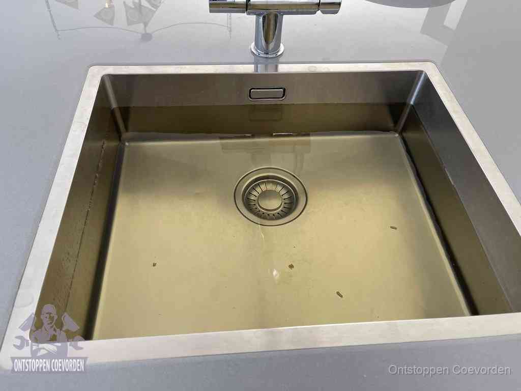 Stilstaand water in een rvs spoelbak dat niet wegloopt, een duidelijk signaal van een gootsteenverstopping in Coevorden