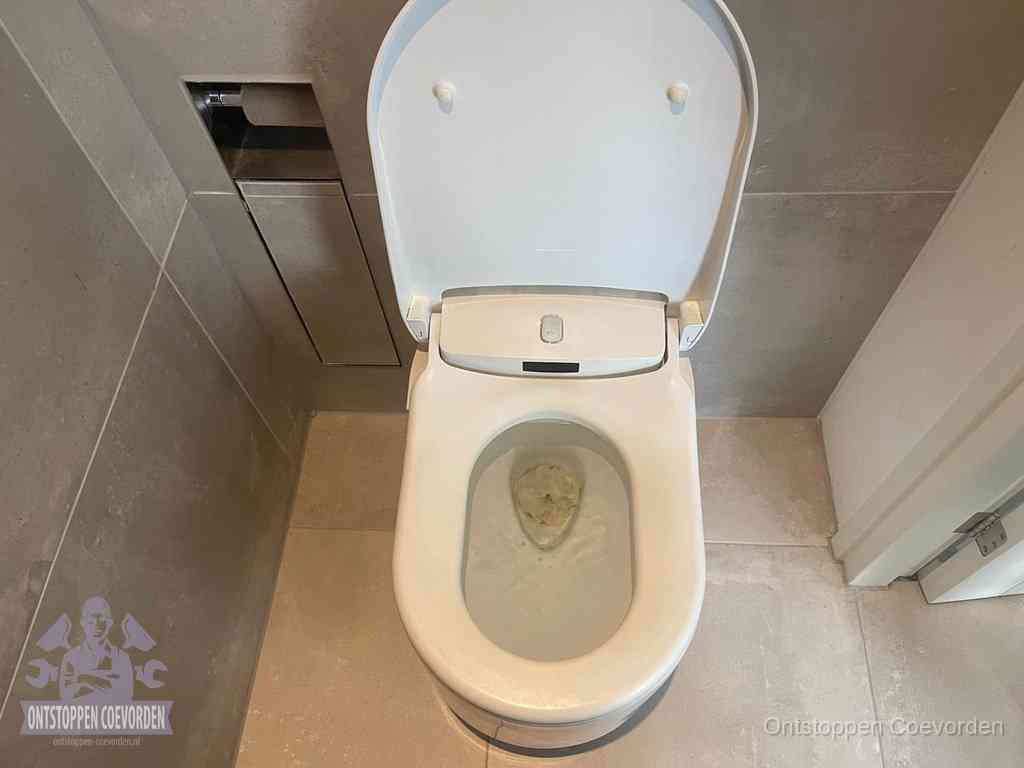 Een wit hangtoilet waarin een prop wc-papier op het water blijft drijven, een duidelijk signaal van een verstopte wc in Coevorden