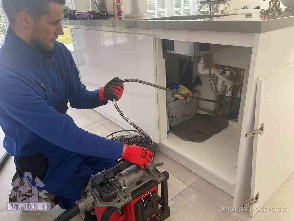 Een monteur reinigt de keukenafvoer grondig met een veermachine om terugkerende gootsteenverstoppingen te voorkomen in Coevorden