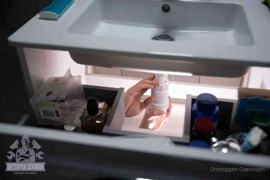 Een pompfles met zeep boven een wastafel in de toiletruimte, de warm water en afwasmiddel-methode om de wc te ontstoppen in Coevorden