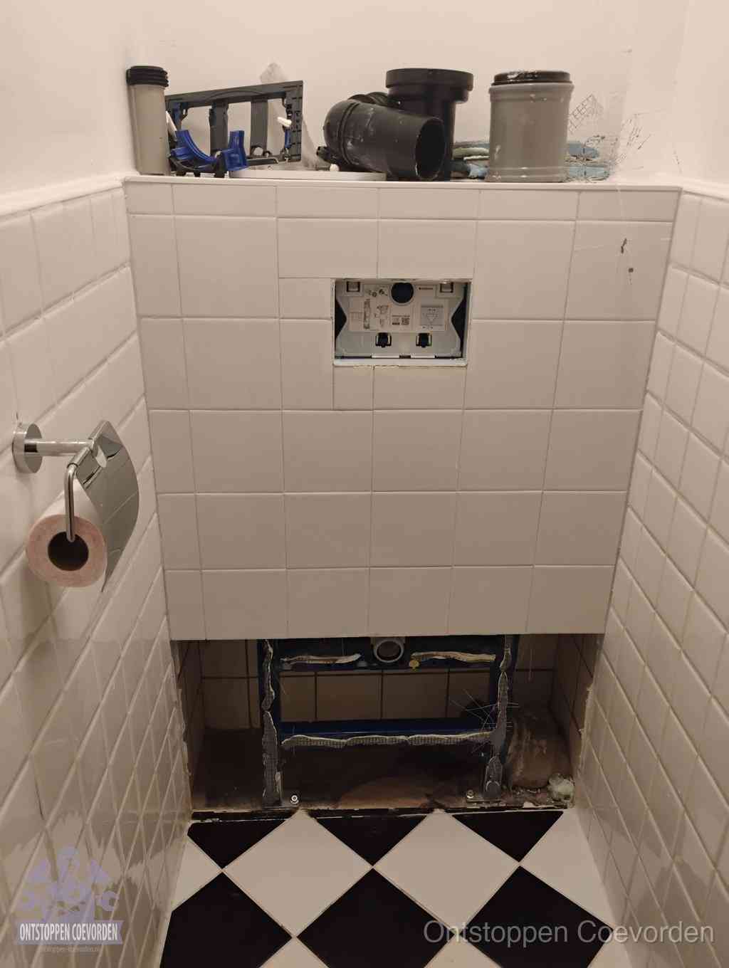 Een toiletruimte waar het hangtoilet en de inbouwreservoir-onderdelen zijn vrijgelegd voor onderhoud, periodiek nazicht voorkomt een wc-verstopping in Coevorden